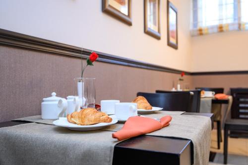 a table with two plates of croissants and a rose at Parklands Hotel & Pool in Bansko