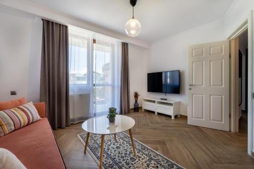 a living room with a couch and a tv and a table at Urbio Private Suites in Cluj-Napoca