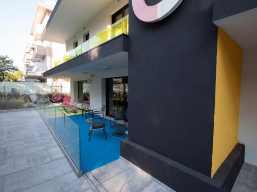 a building with a blue and yellow wall and chairs at Demo Hotel Design Emotion in Rimini
