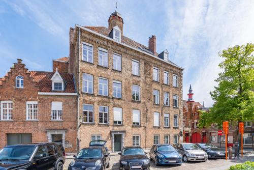 een groot bakstenen gebouw met auto's geparkeerd voor het bij Modern guest house in centre of Bruges in Brugge