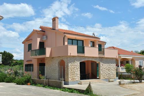 a large pink house with a balcony at Apartments Sunny Punta in Privlaka