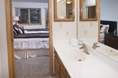 ein Bad mit einem Waschbecken, einem Spiegel und einem Bett in der Unterkunft Townsend Place 206A Condo in Beaver Creek