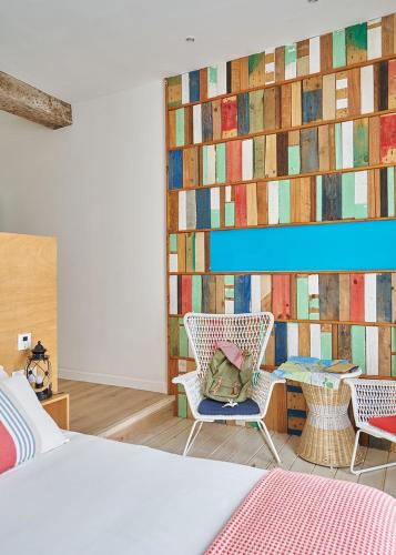 a bedroom with a bed and two chairs and a wall with a painting at Urban Suite Santander in Santander