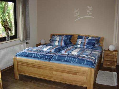 ein Schlafzimmer mit einem Bett mit blauer Decke und einem Fenster in der Unterkunft Ferienwohnung-Jung in Bad Sachsa