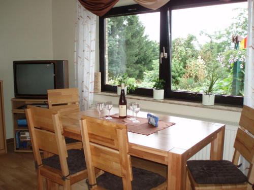 einen Esstisch mit Stühlen und eine Flasche Wein in der Unterkunft Ferienwohnung-Jung in Bad Sachsa