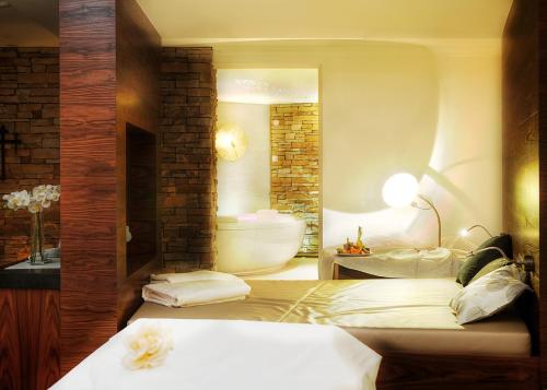 a bathroom with a tub and a bed and a sink at Wellnesshotel Cervosa in Serfaus