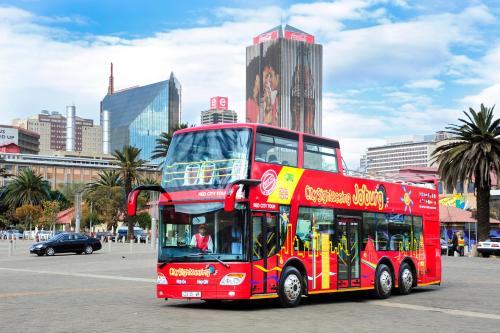 a red double decker bus on a city street at Premier Hotel O.R. Tambo in Kempton Park