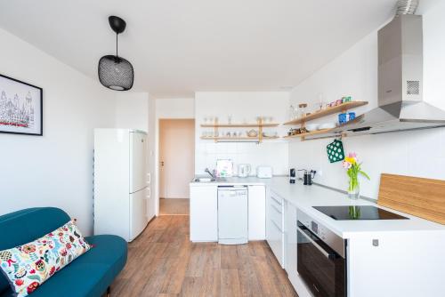 a kitchen with white counters and a blue chair at BRIGHT CHARMING Apt with TERRACE, PARKING & AirCo. in Prague