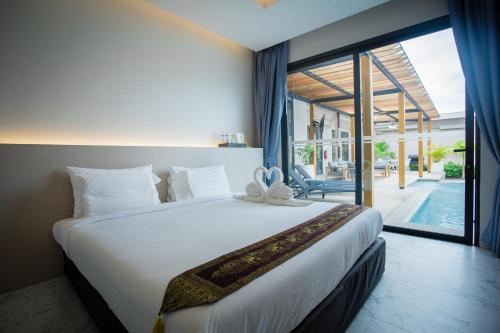 ein Schlafzimmer mit einem großen Bett und einem großen Fenster in der Unterkunft Gold Chariot Pool Villa, Phuket - SHA Plus Certified in Strand Bang Tao