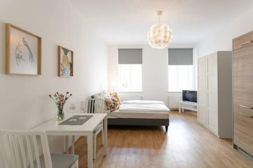 a white living room with a bed and a table at Studio-Apartment between Schoenbrunn & the City Center (13) in Vienna