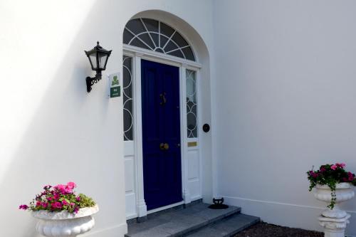 a blue door on a white house with flowers at Cannaway House B&B in Macroom