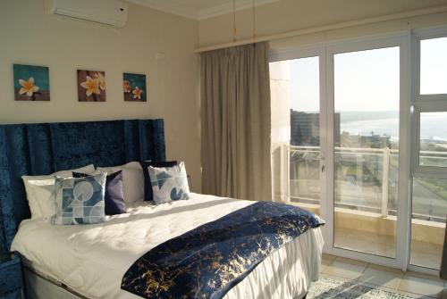 a bedroom with a bed and a large window at Luxury Apartment 23 @ Seahorse with 180° seaview in Scottburgh