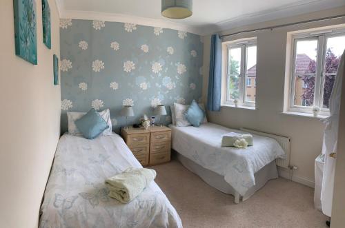 a bedroom with two beds and two windows at Willow Farm Way in Herne Bay