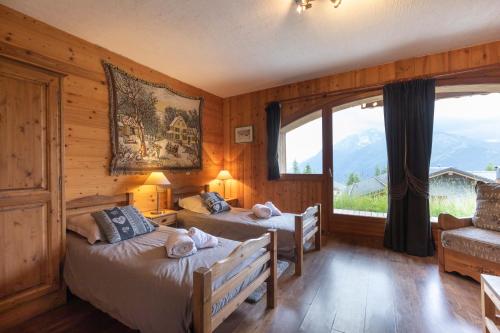 a bedroom with two beds and a large window at Chalets Kandahar - Mountain Collection in La Rosière