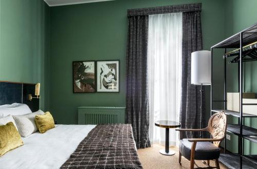 a bedroom with green walls and a bed and a chair at 4F Boutique Hotel Florence in Florence