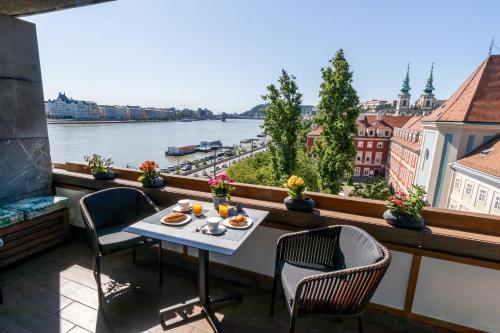 a table and chairs on a balcony with a view of a river at Danube Pearl Boutique Apartment in Budapest