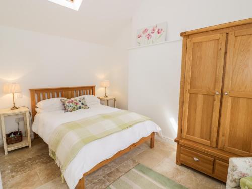 a bedroom with a bed and a wooden cabinet at The Apple Barn in Daventry