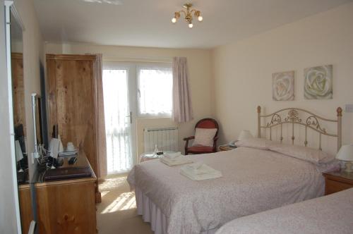 1 dormitorio con 2 camas, lavabo y TV en Hotel La Michele en St Martin Guernsey