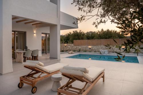 a villa with a swimming pool and two lounge chairs at Anthos Villas - Chania in Tavronitis