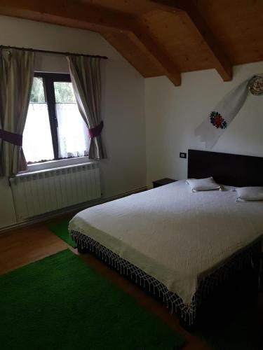 a bedroom with a large bed and two windows at Cabana Alexandra in Moisei