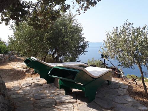 a green bench sitting on top of a hill at Robinson Galisnjak with amazing SEA VIEW & JACUZZI in Bol