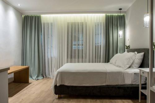 a bedroom with a large bed with green curtains at Isidorou Suite Xanthi in Xanthi