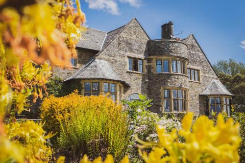 an old stone house with a garden in front of it at Cragwood Country House Hotel in Windermere