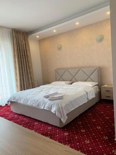 a bedroom with a large bed with a red carpet at Hotel Veștem in Veştem