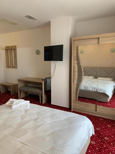 a bedroom with a bed and a desk and a television at Hotel Veștem in Veştem