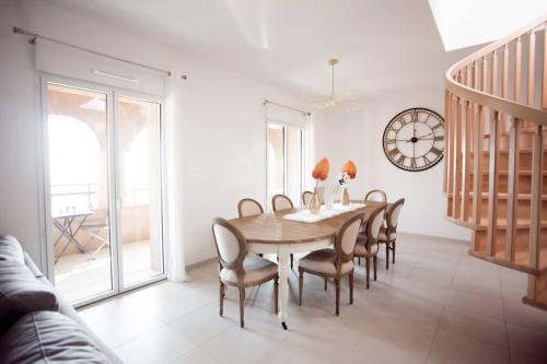 une salle à manger avec une table, des chaises et une horloge dans l'établissement Magnifique appartement avec vue imprenable, à La Londe-les-Maures