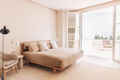 a white bedroom with a bed and a balcony at Plácido y Grata in Seville
