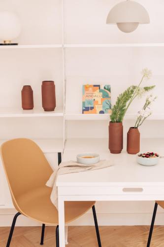 a white dining room table and chairs with plants at Plácido y Grata in Seville