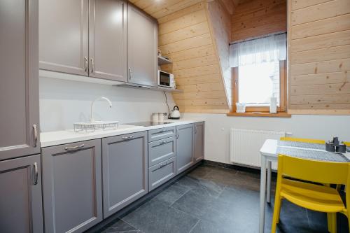 uma cozinha com armários cinzentos, uma mesa e cadeiras amarelas em Osada Witów - apartament „Czerwone Wierchy” em Witów