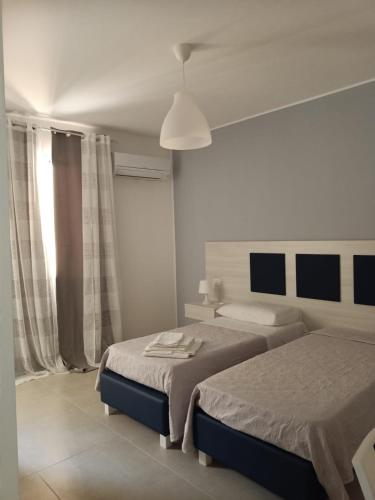 ein weißes Schlafzimmer mit 2 Betten und einem Fenster in der Unterkunft La Lume in Partanna