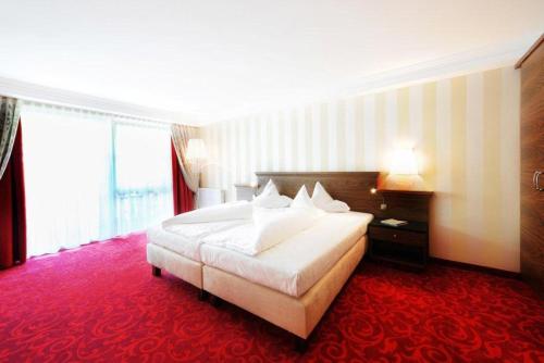 a hotel room with a large bed and a red carpet at Wellnesshotel Cervosa in Serfaus