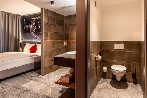 a bathroom with a bed and a toilet and a sink at Aiden by Best Western Stadtgut Hotel Steyr - FREE PARKING in Steyr