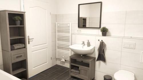 a white bathroom with a sink and a mirror at Ferienwohnungen in ausgebauter Scheune mit Ostseenähe in Zarnekow