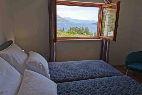 a bedroom with a bed and a window with a view at Deluxe apartman “ Koromačna” in Korčula