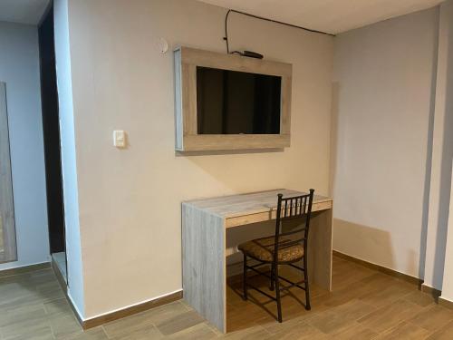 a desk with a chair and a television on a wall at Terraza Dreams in Quito
