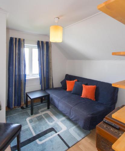 a living room with a blue couch with orange pillows at Mandal Apartment mit Möglichkeit ein Boot zu benutzen und Angeln in Mandal