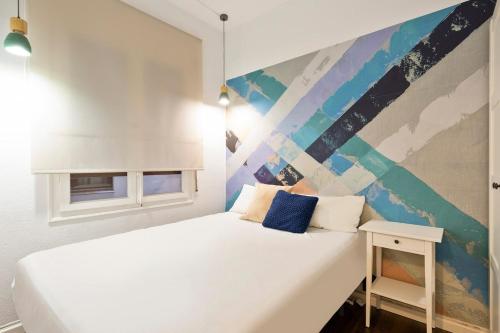 a bedroom with a white bed with a painting on the wall at Stay U-nique Apartments Estación del Norte in Barcelona