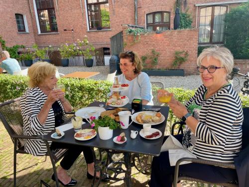 three women sitting at a table eating food at Boutique Hotel The Roosevelt in Middelburg