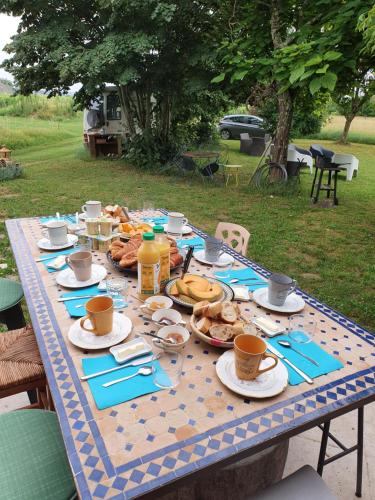 einen Tisch mit Teller mit Essen und Tassen darauf in der Unterkunft 299 Bigaroux in Saint-Émilion
