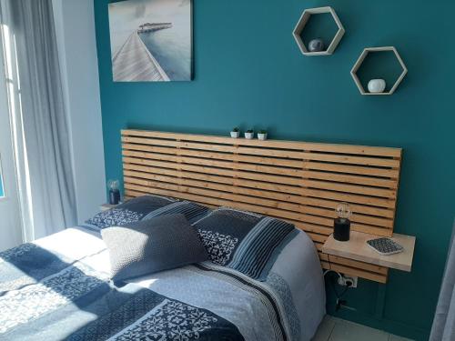 une chambre bleue avec un lit et une tête de lit en bois dans l'établissement Beau studio avec balcon, à Bagnères-de-Bigorre