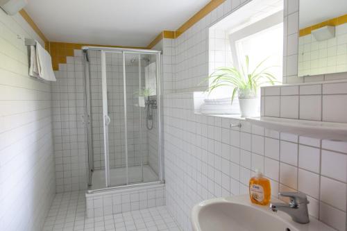 a white tiled bathroom with a shower and a sink at Rotel Inn in Passau