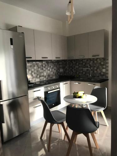 Cyclops Luxury Apartments في إيغومينيتسا: مطبخ مع طاولة وكراسي وثلاجة
