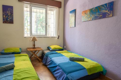 two twin beds in a room with a window at Natural Mystic Hostel in Costa da Caparica