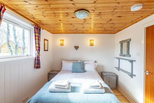 a bedroom with a bed and a wooden ceiling at Bracken Lodge 16 with Hot Tub in Belladrum