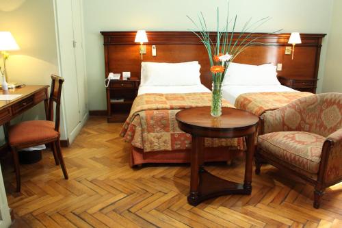 a hotel room with a bed and a table with a vase on it at Hotel Colonial San Nicolás in San Nicolás de los Arroyos
