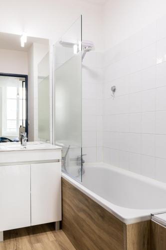 une salle de bain blanche avec une baignoire et un lavabo dans l'établissement DIFY Victoire, à Lyon